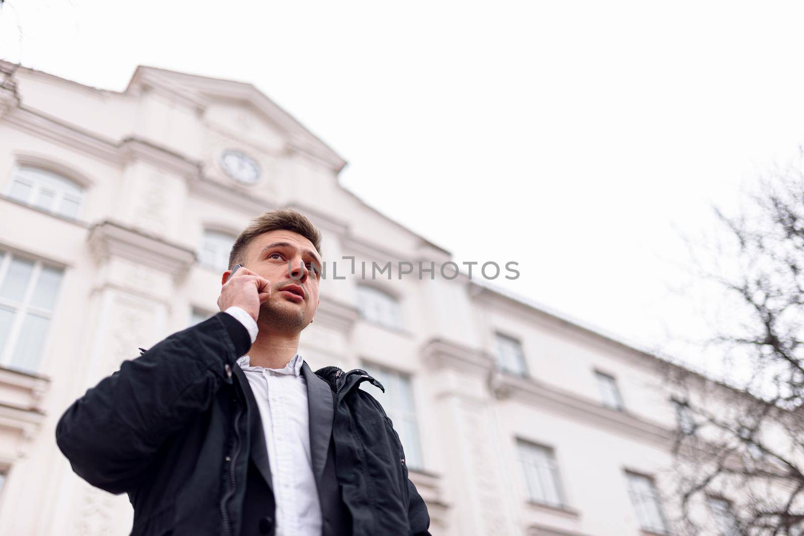 Portrait of handsome guy standing on the street while talking on mobile phone. Copy space. Lifestyle concept