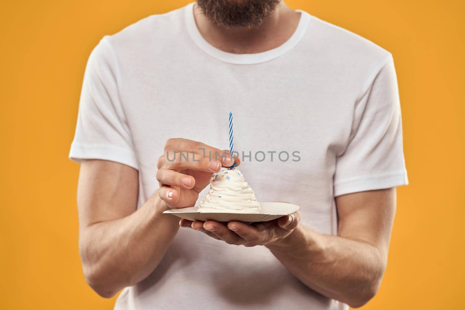 A man with a birthday cake in his hands on a yellow background birthday dessert. High quality photo