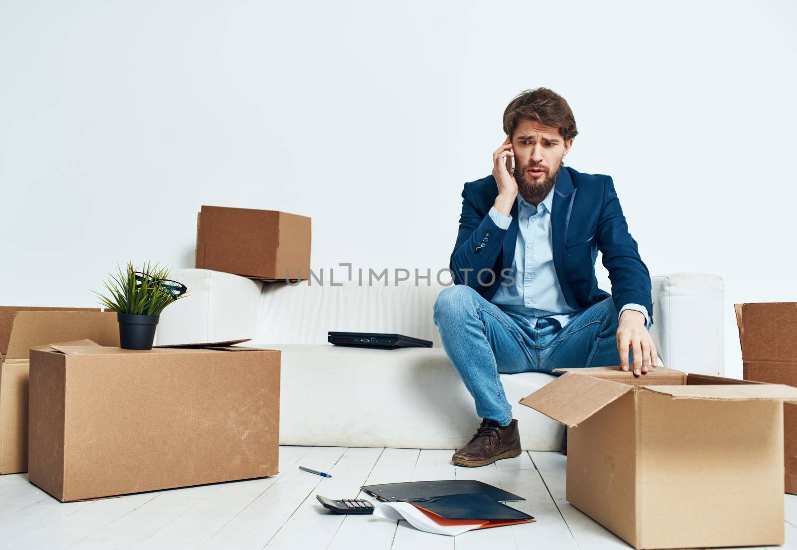 Business man with laptop sitting on sofa unpacking boxes official. High quality photo