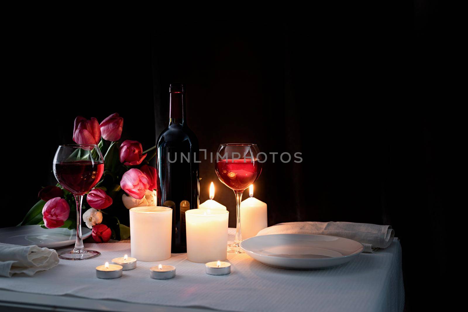 Romantic candlelight dinner with wine, candles and tulip bouquet
