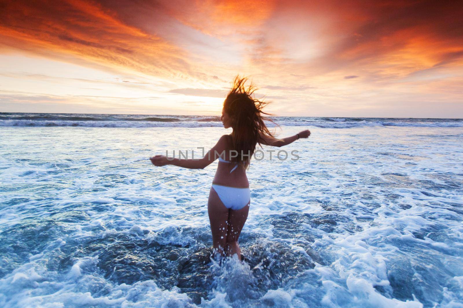 Happy Woman in bikini Jumping in Sea Sunset