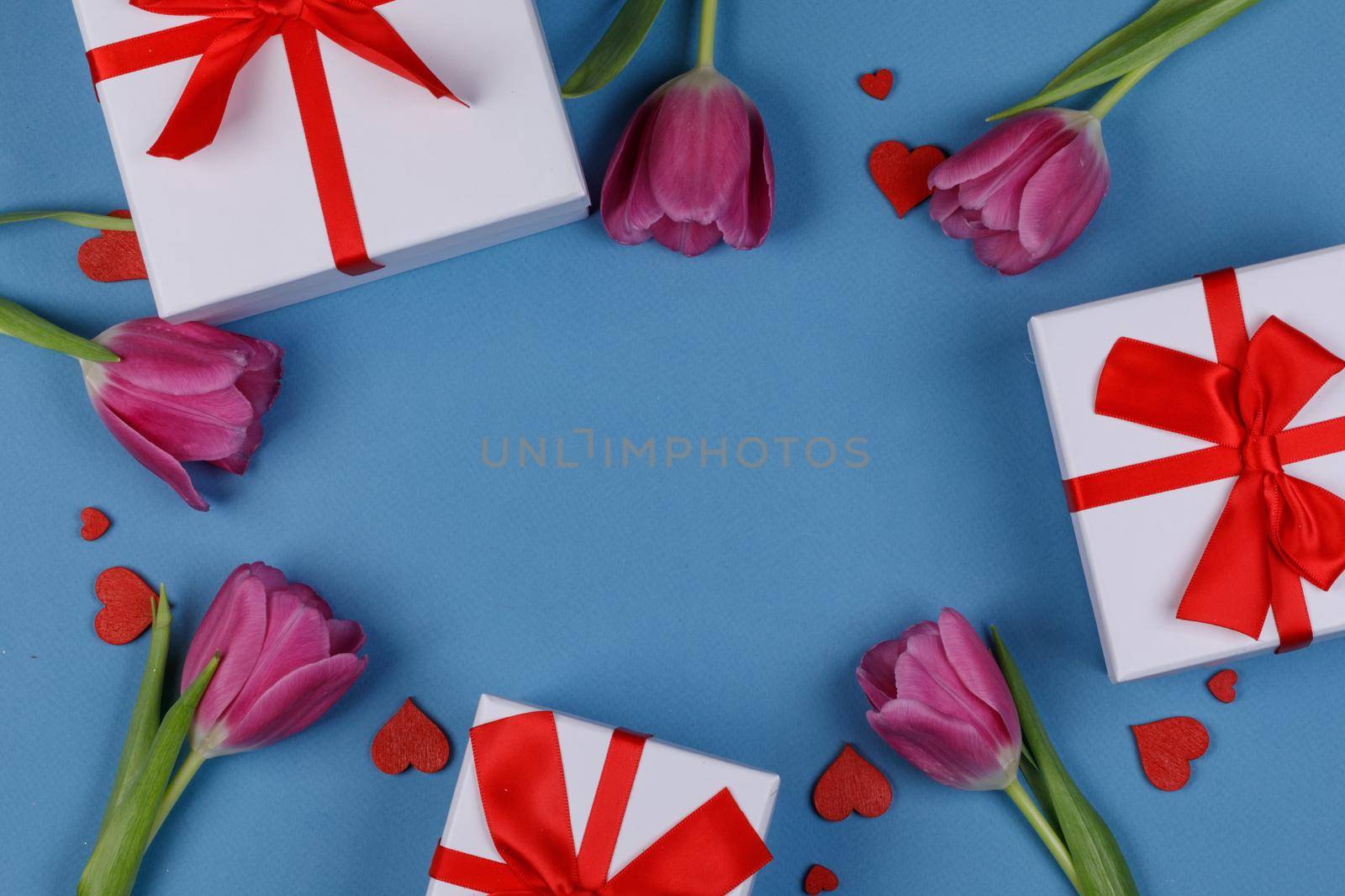 Pink tulip flowers gifts red hearts and gifts composition on blue background top view with copy space. Valentine's day, birthday, wedding, Mother's day concept. Copy space