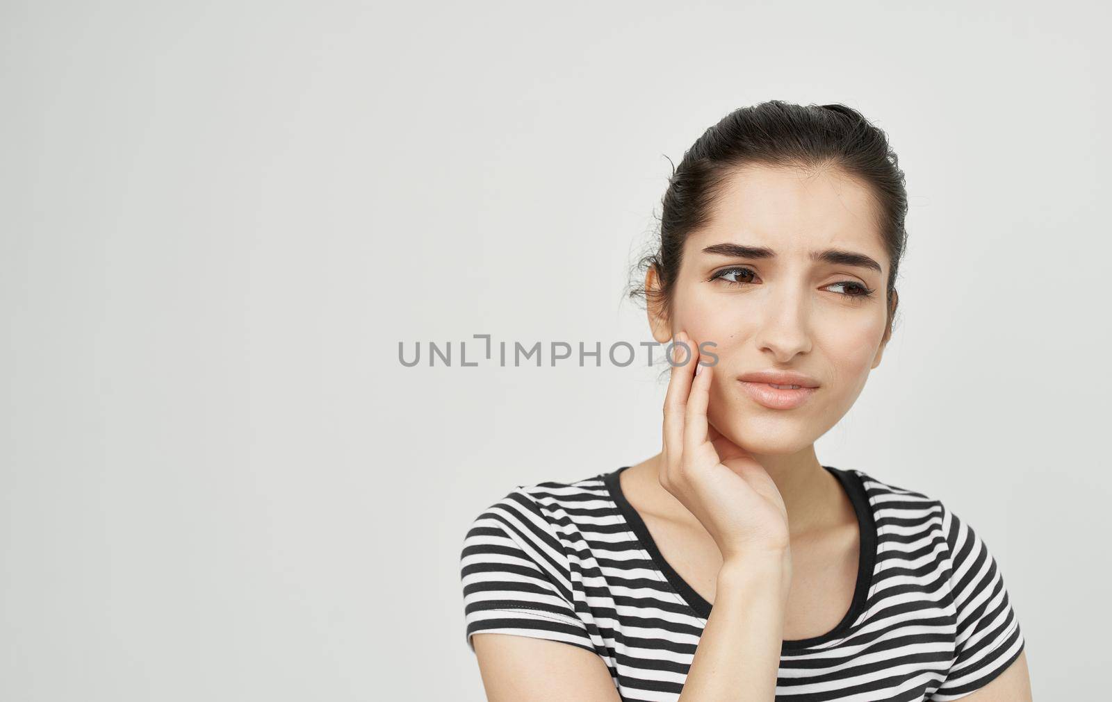 woman in striped t-shirt holding face dental problems pain discontent by SHOTPRIME