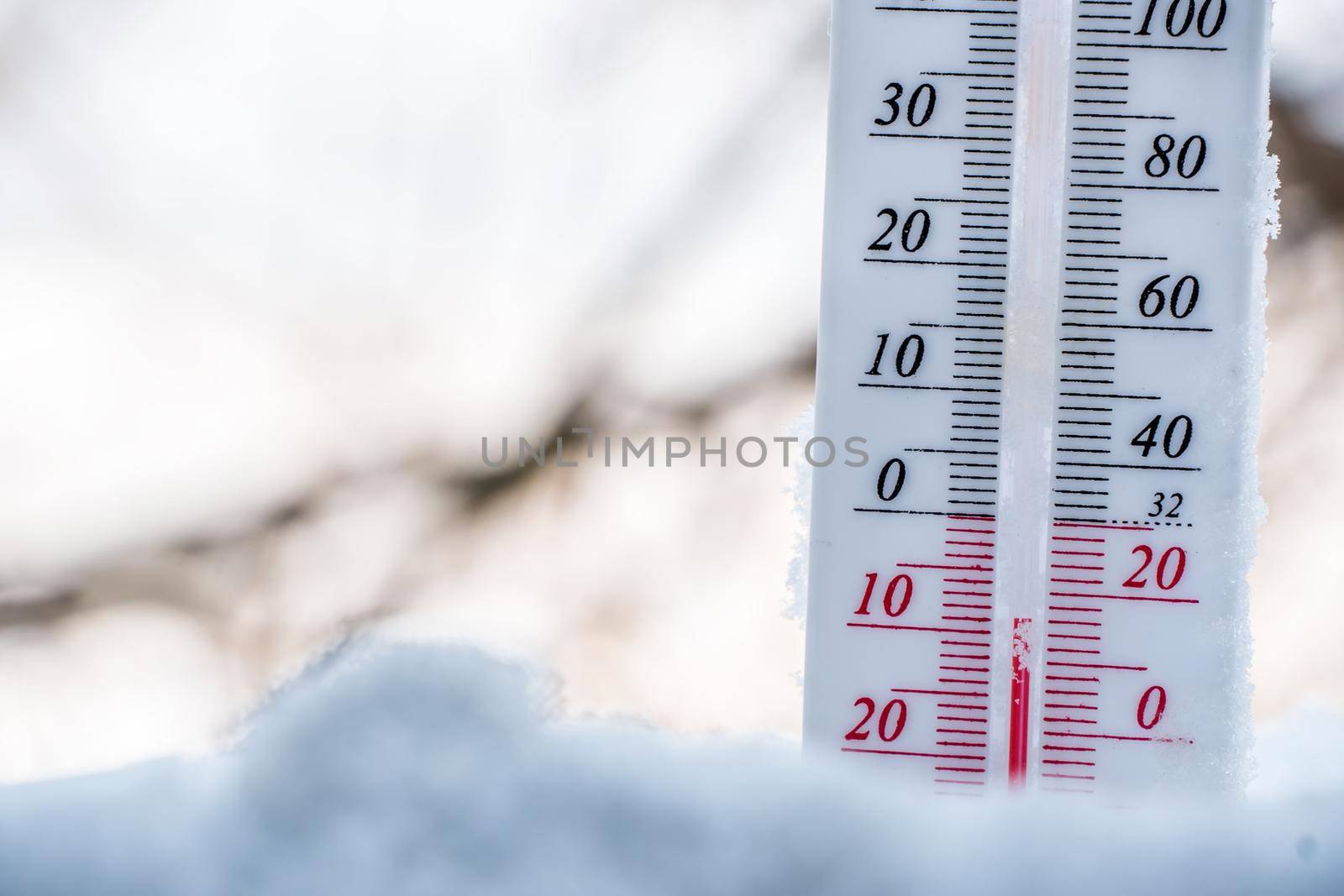 The thermometer lies on the snow in winter showing a negative temperature. Meteorological conditions in a harsh climate in winter with low air and ambient temperatures.Freeze in wintertime