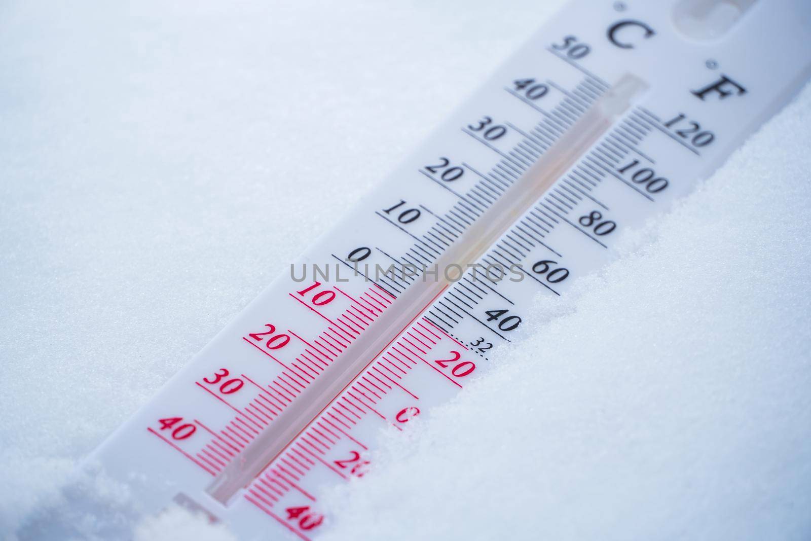 The thermometer lies on the snow in winter showing a negative temperature. Meteorological conditions in a harsh climate in winter with low air and ambient temperatures.Freeze in wintertime by YevgeniySam