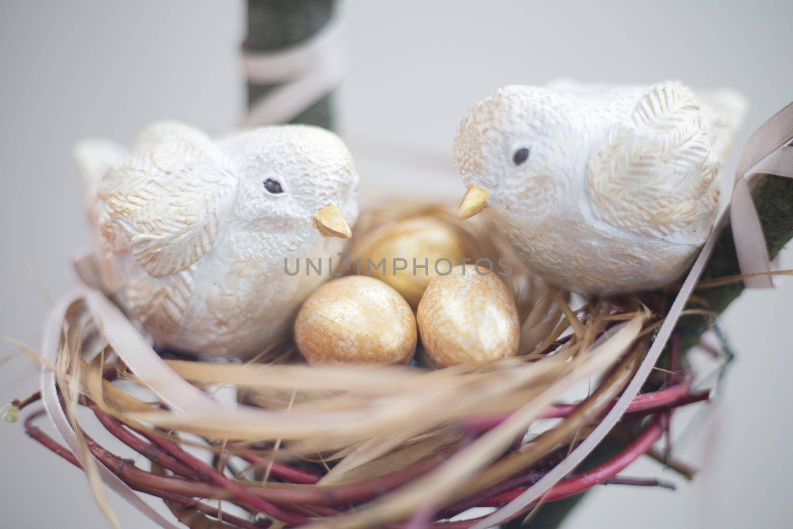 Two cute handmade small birds and their golden eggs in nest , parentind, care, easter concept