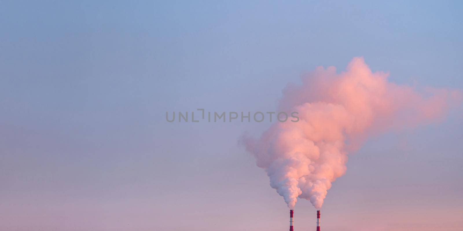 Smoke from chimneys of heating plant. Air pollution. Factory pipes with smoke, frosty weather, sunrise. Ecology problem. Copy space