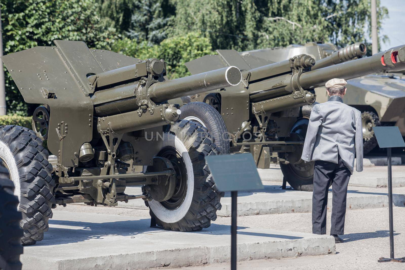 Old man stands near military cannons in victory park