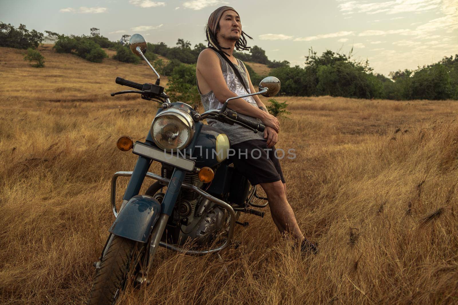 A man stands near a motorcycle in a field by snep_photo