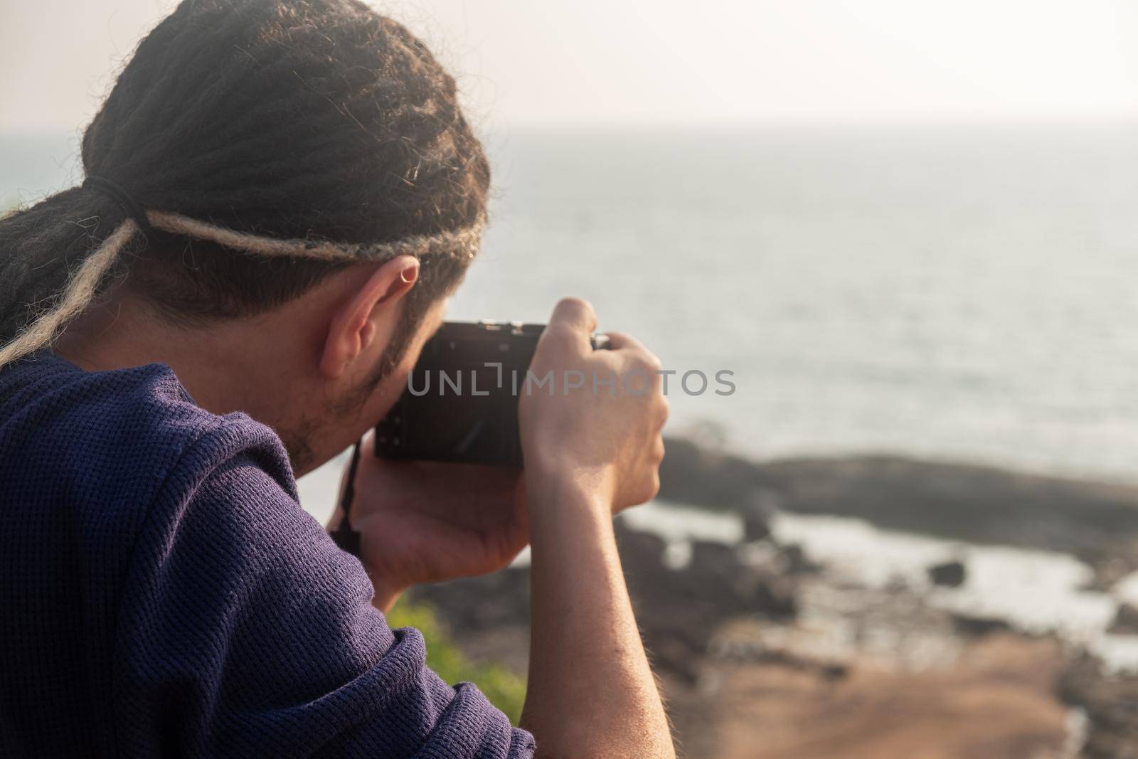 Young Asian photographer taking a picture from the top of a mountain, Northern Goa, India