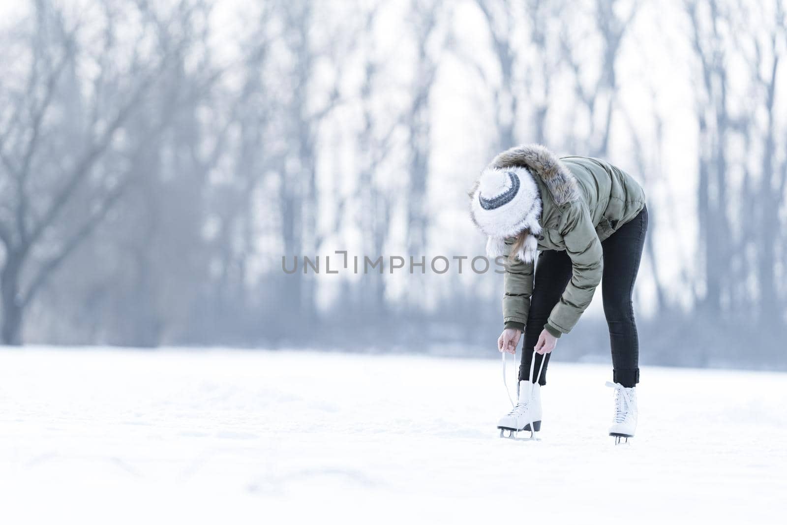 tying the laces of winter skates on a frozen lake