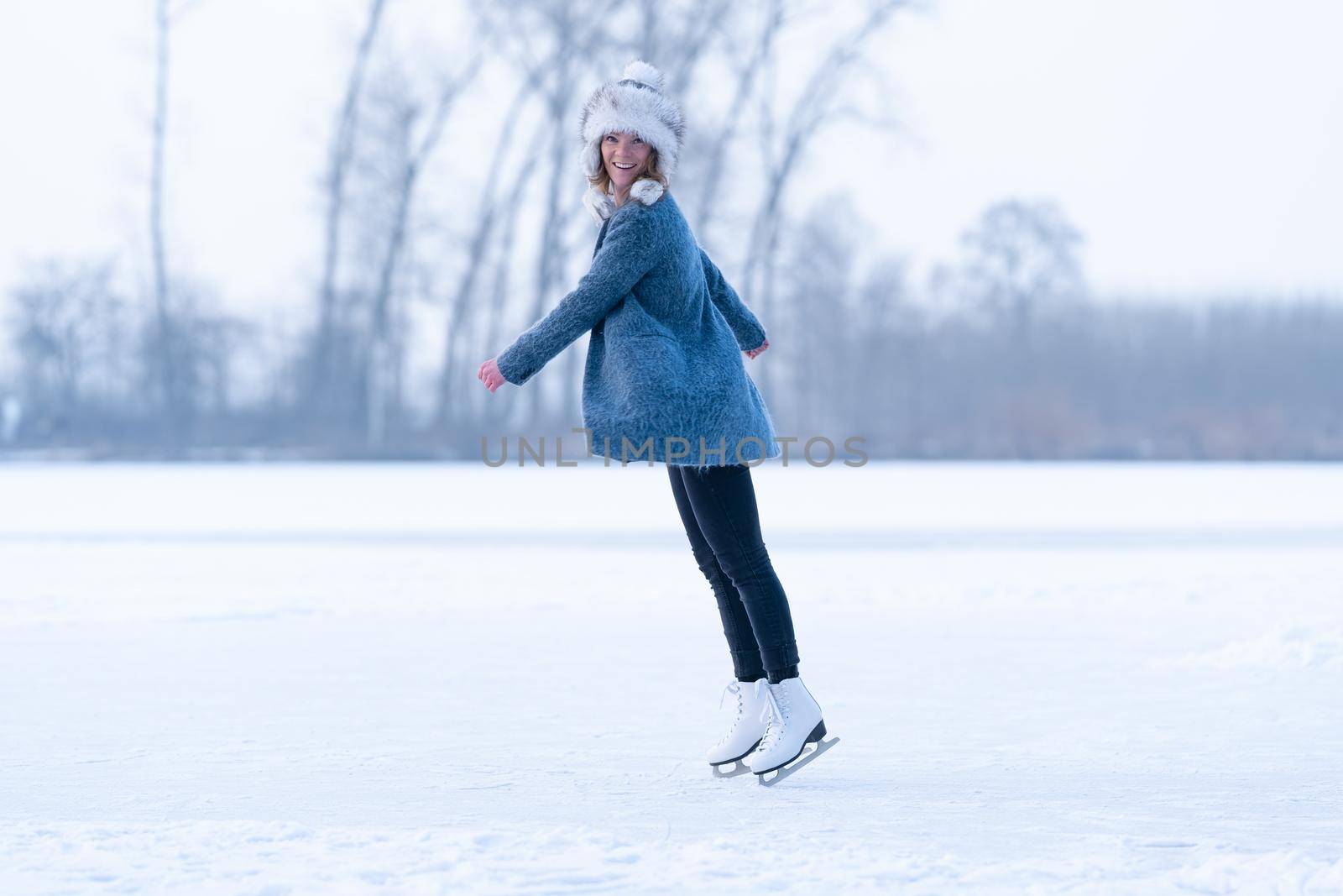 Gorgeous woman skating on frozen lake.