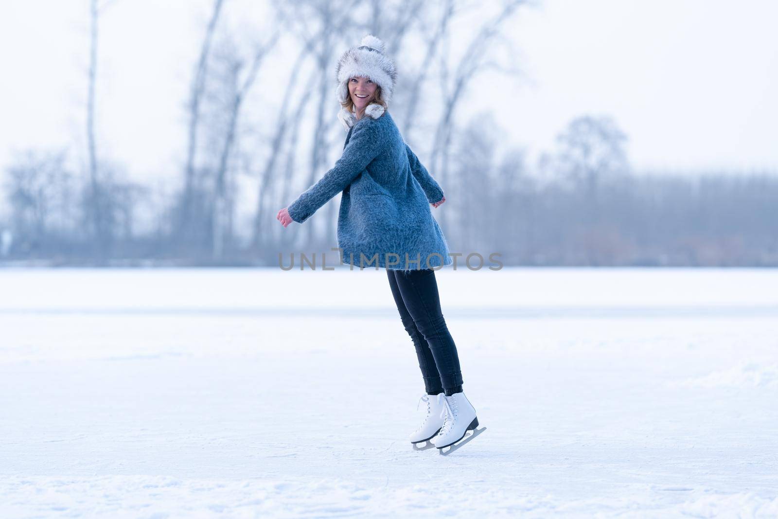 Gorgeous woman skating on frozen lake in winter by Edophoto