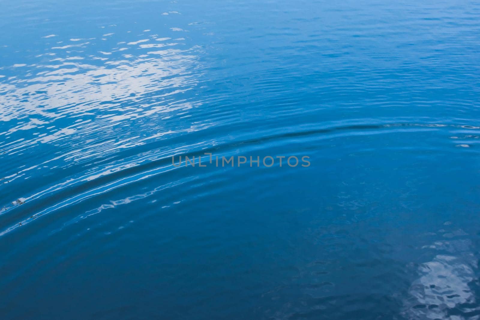 Small ripples on calm water with deep blue reflections. by hernan_hyper