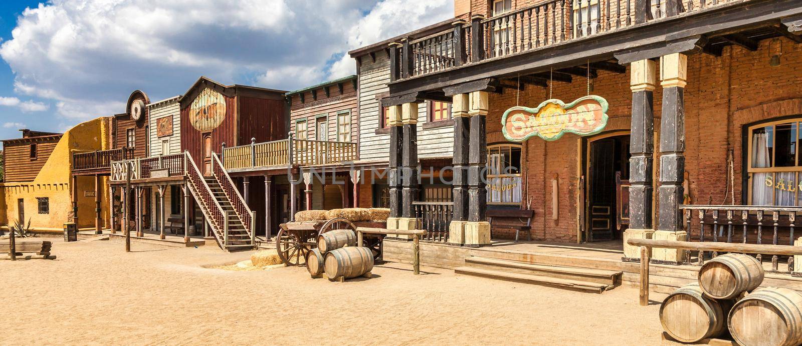 Vintage Far West town with saloon. Old wooden architecture in Wild West with blue sky background.