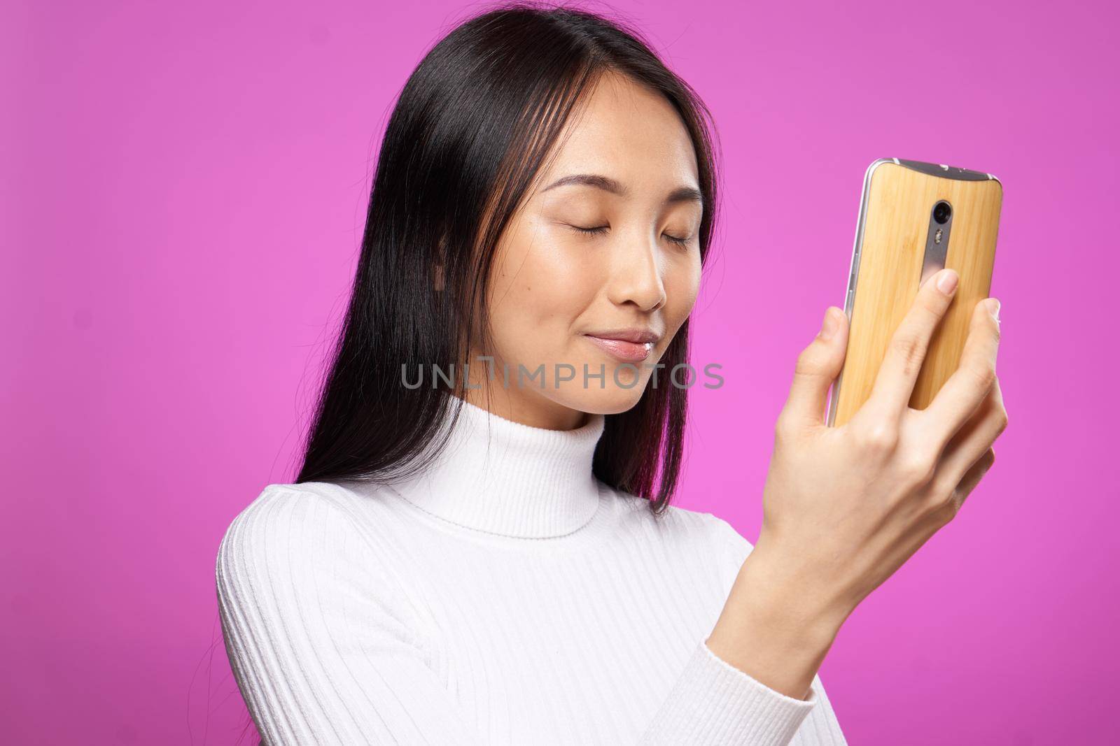 pretty woman in white sweater phone in hands pink background fashion communication by SHOTPRIME