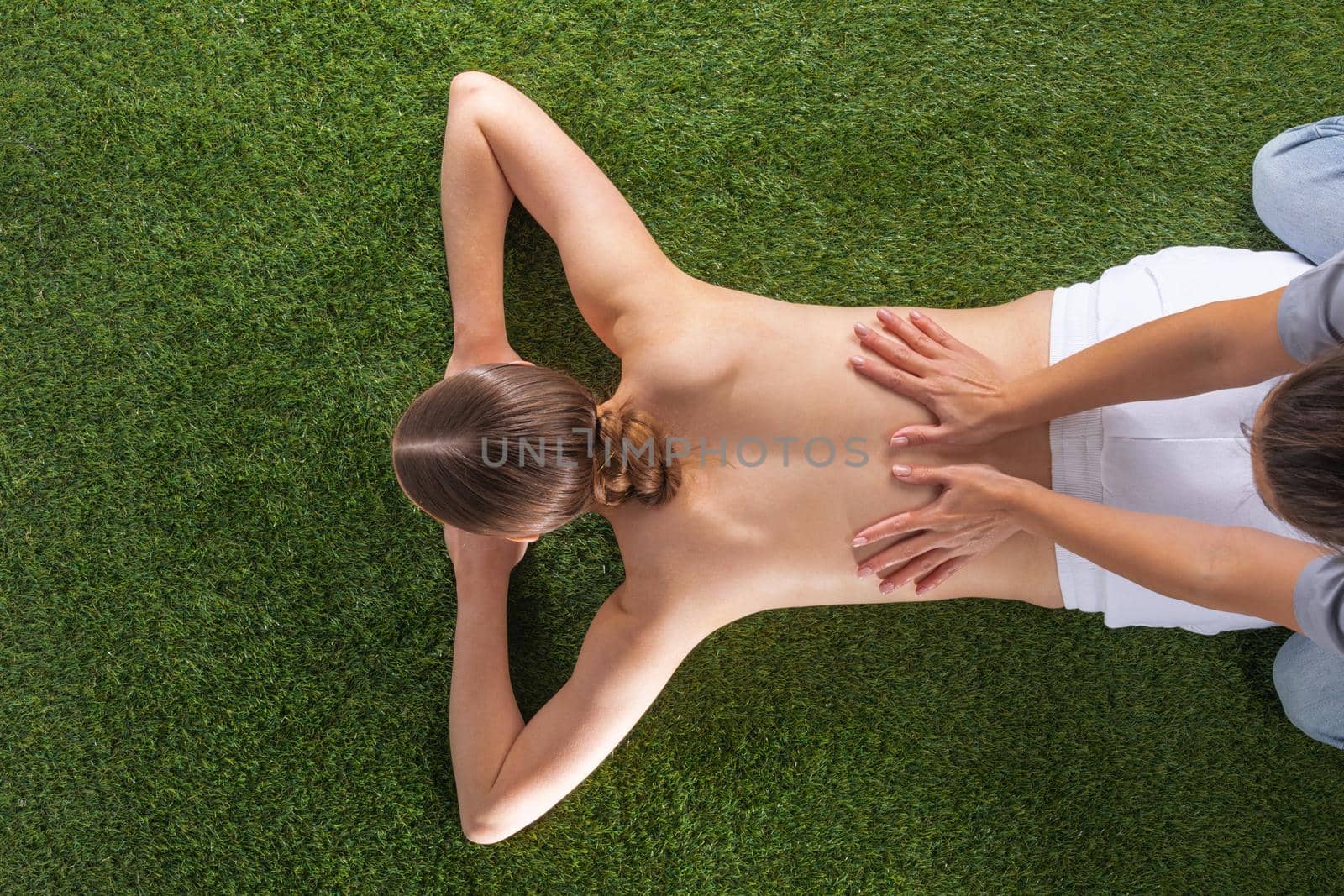 Natural body care concept, woman at spa massage lying on grass, top view