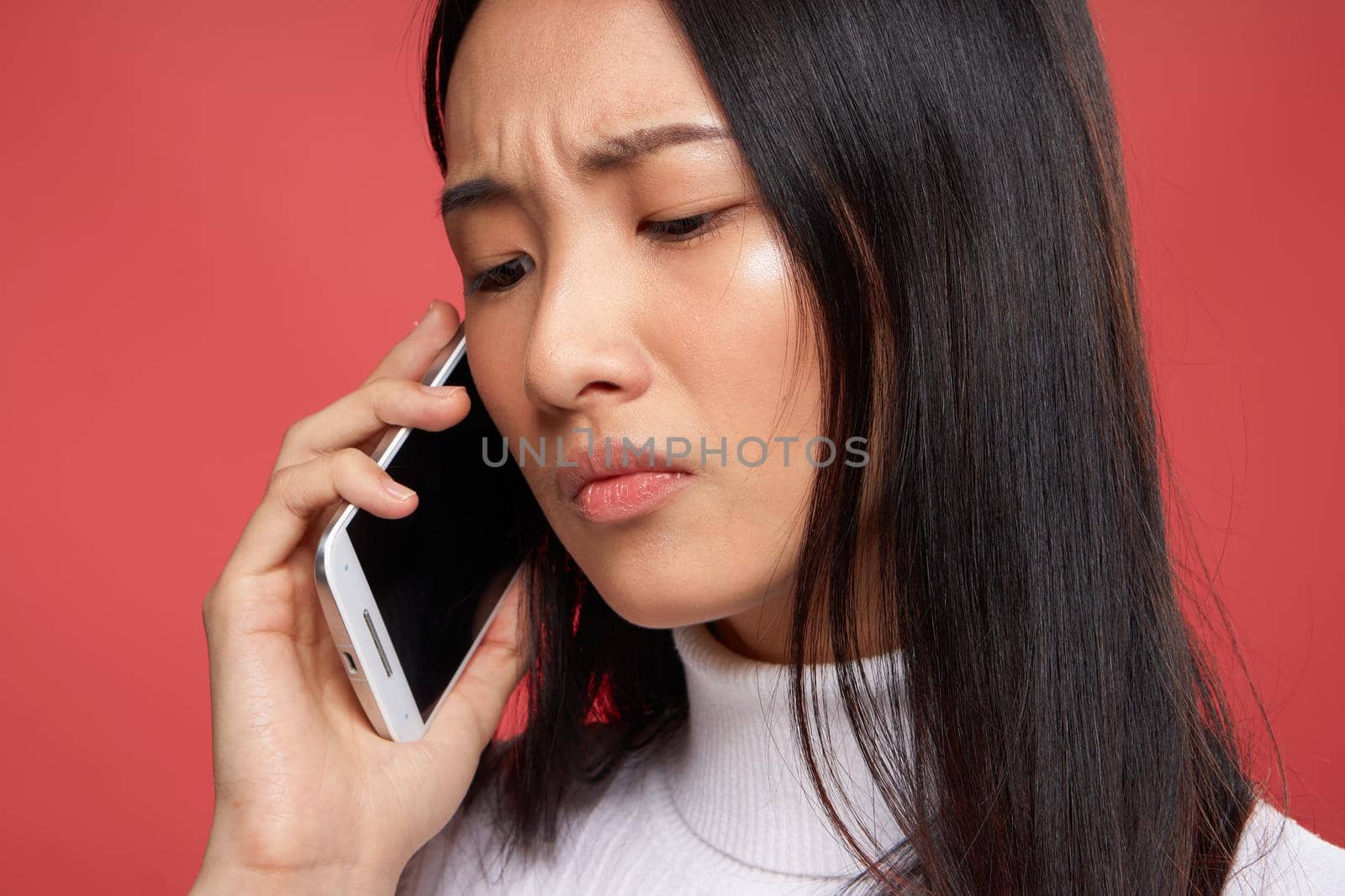 woman of asian appearance and contented facial expression talking on the phone close-up red fund by SHOTPRIME