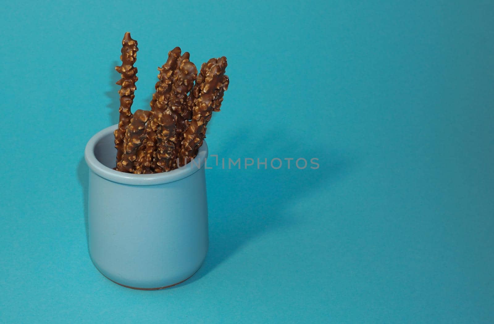 Chocolate crispy sticks with hazelnut sprinkles on a blue background.