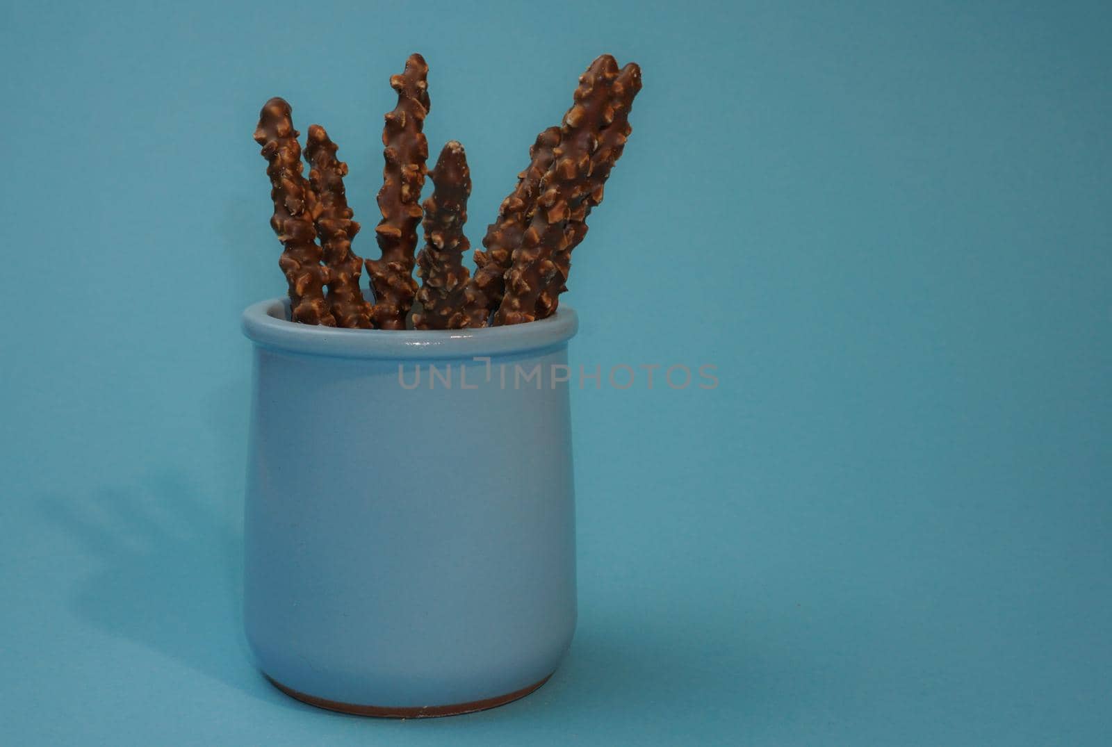 Chocolate crispy sticks with hazelnut sprinkles on a blue background.