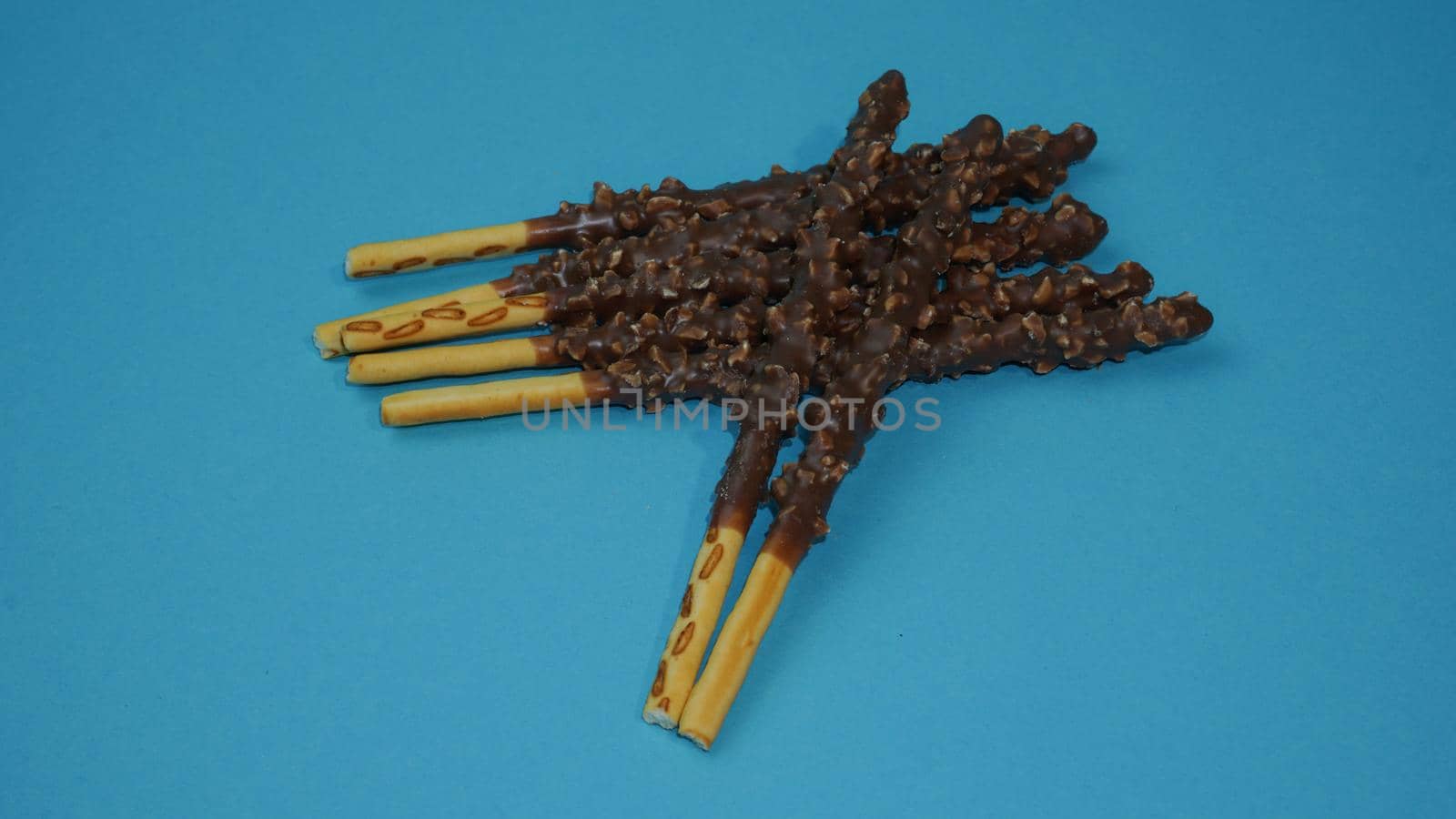 Chocolate crispy sticks with hazelnut sprinkles on a blue background.