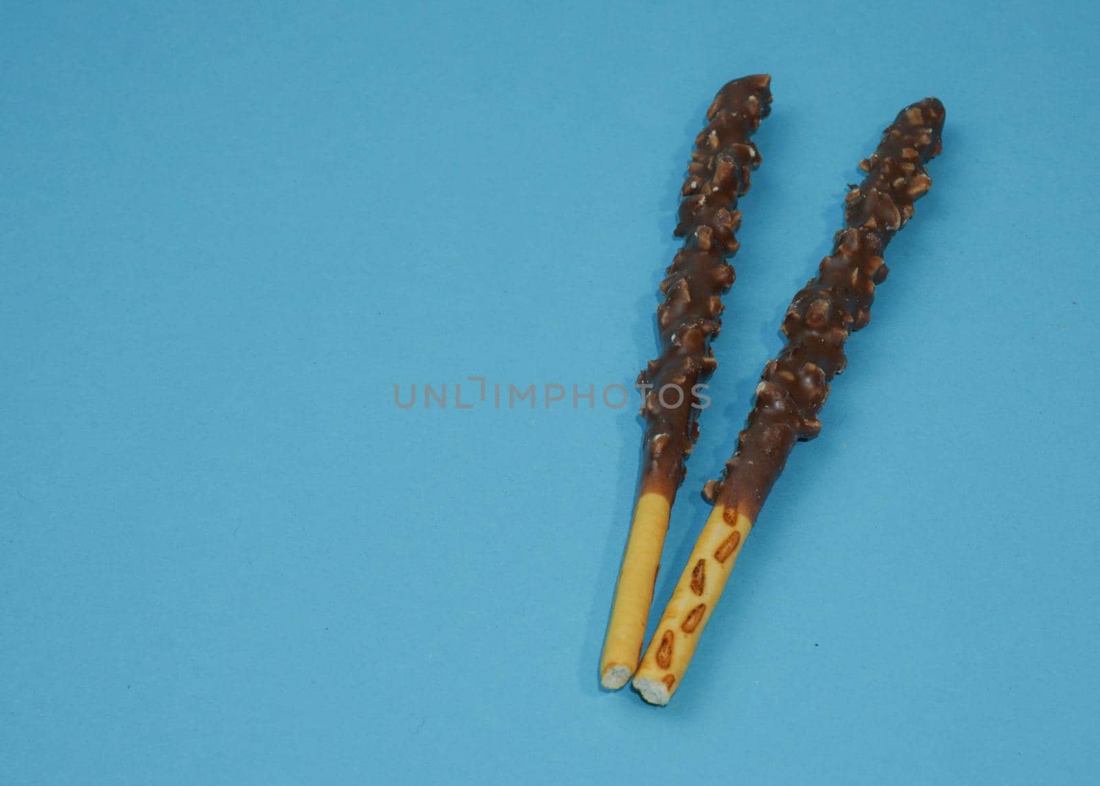 Chocolate crispy sticks with hazelnut sprinkles on a blue background.