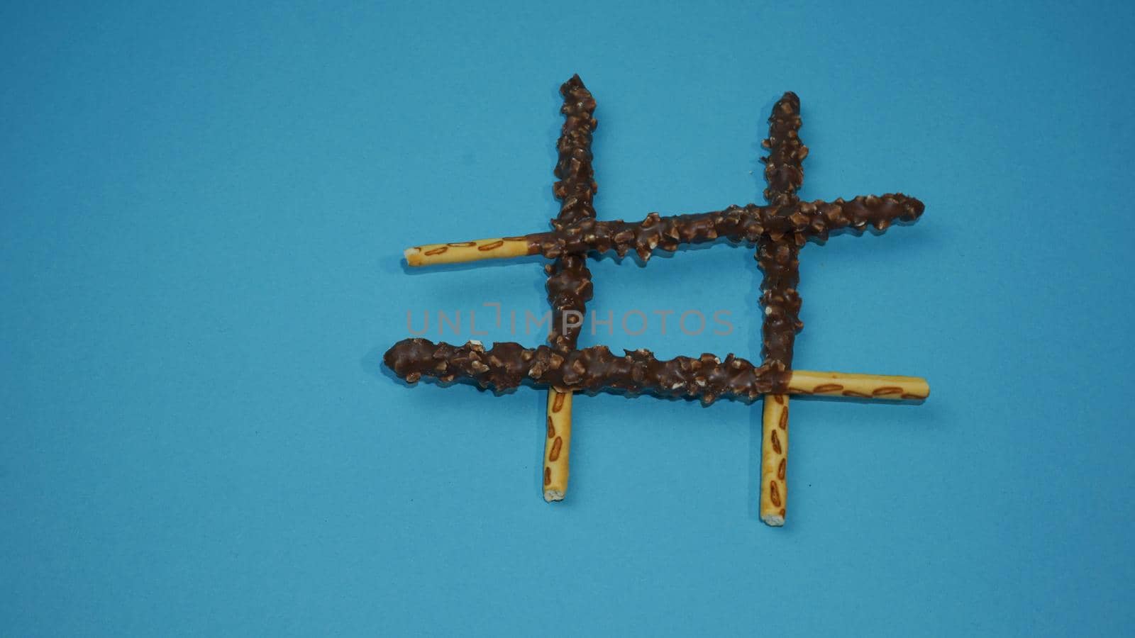 Chocolate crispy sticks with hazelnut sprinkles on a blue background.