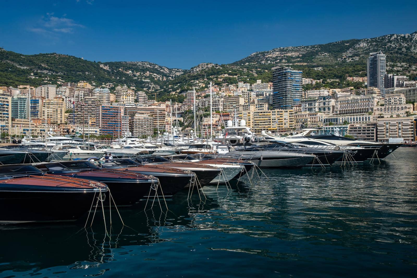 Monaco, Monte-Carlo, 06 August 2018: Tranquillity in port Hercules, is the parked boats, sunny day, many yachts and boats, a lot of Rivas boats, megayachts, massif of expensive real estate by vladimirdrozdin