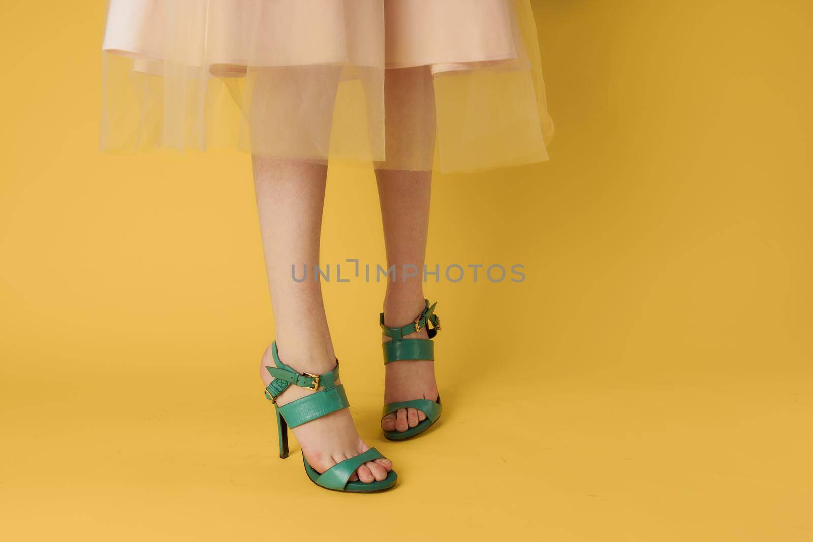 Female feet green shoes elegant style fashionable shoes yellow background. High quality photo