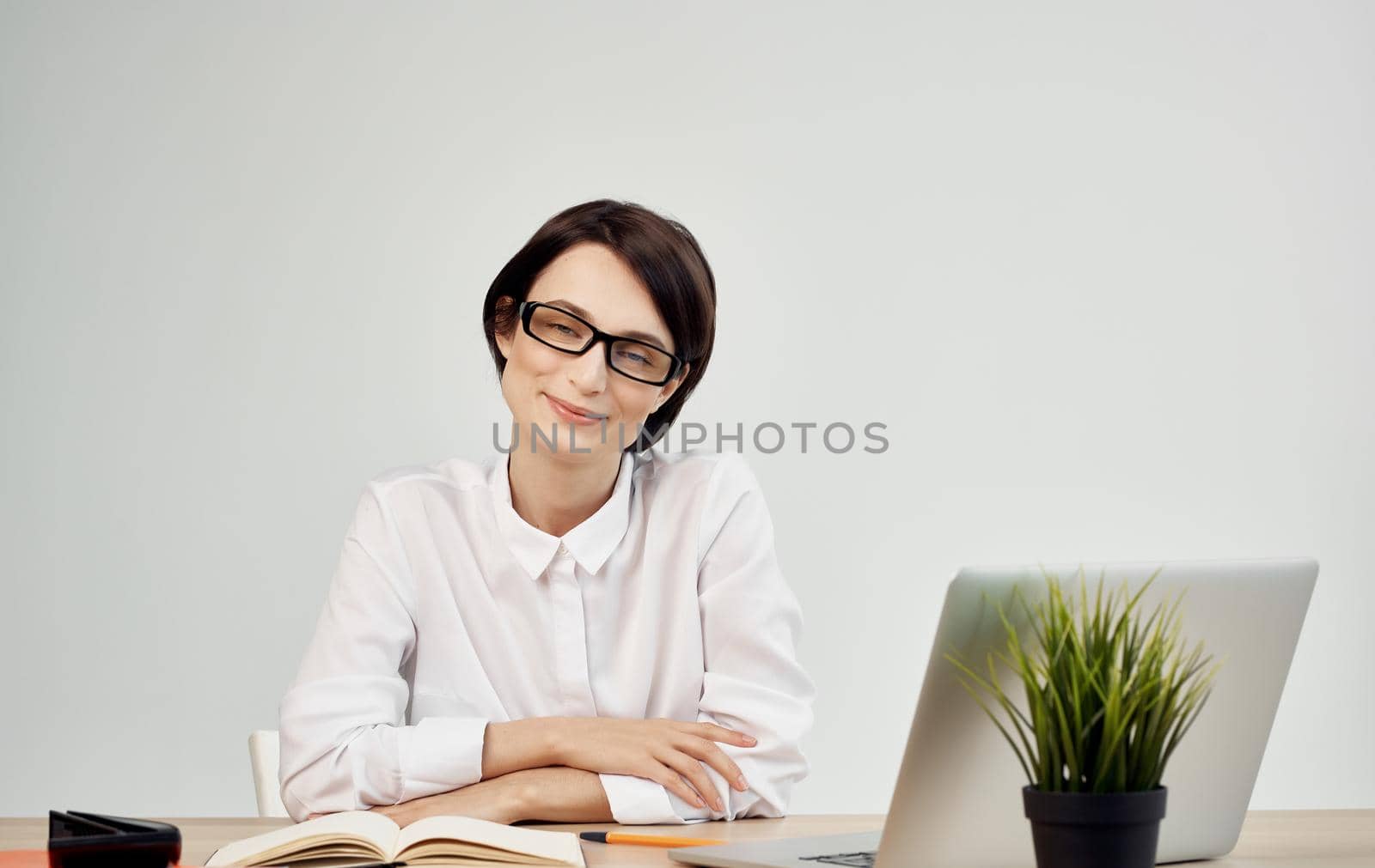 woman sitting at her desk wearing glasses in front of laptop office manager executive. High quality photo