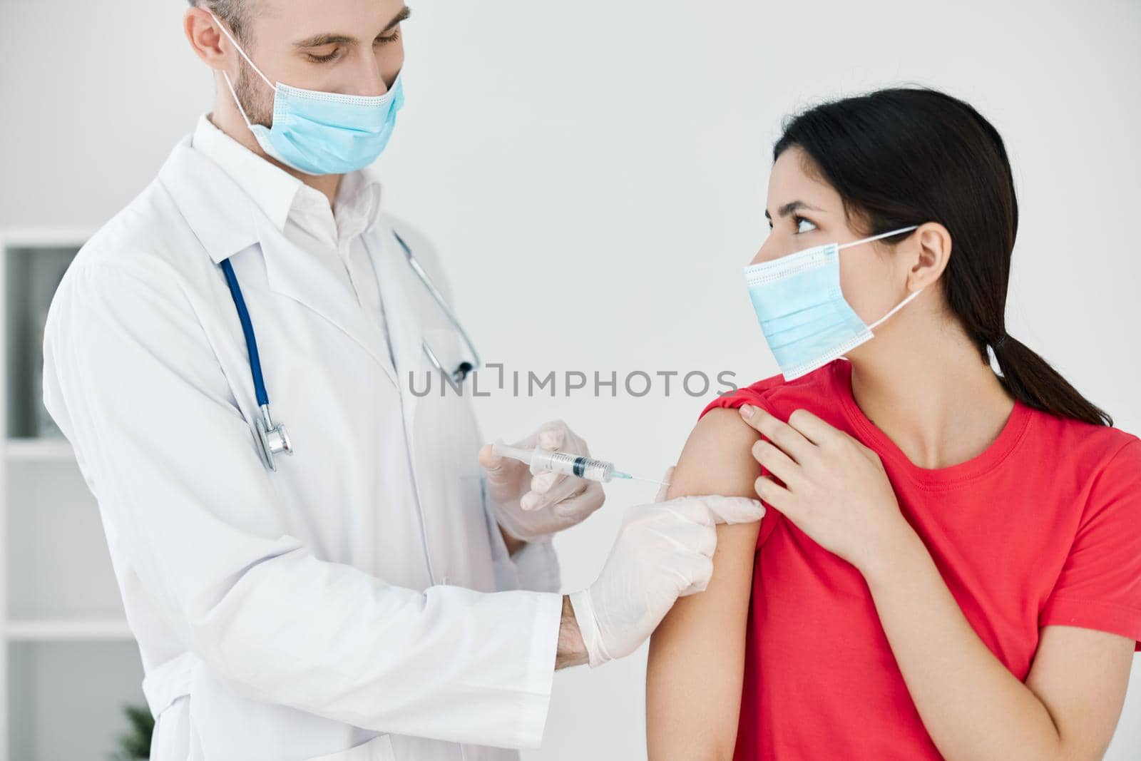 the doctor makes an injection into the patient's arm with a medical mask plan. High quality photo