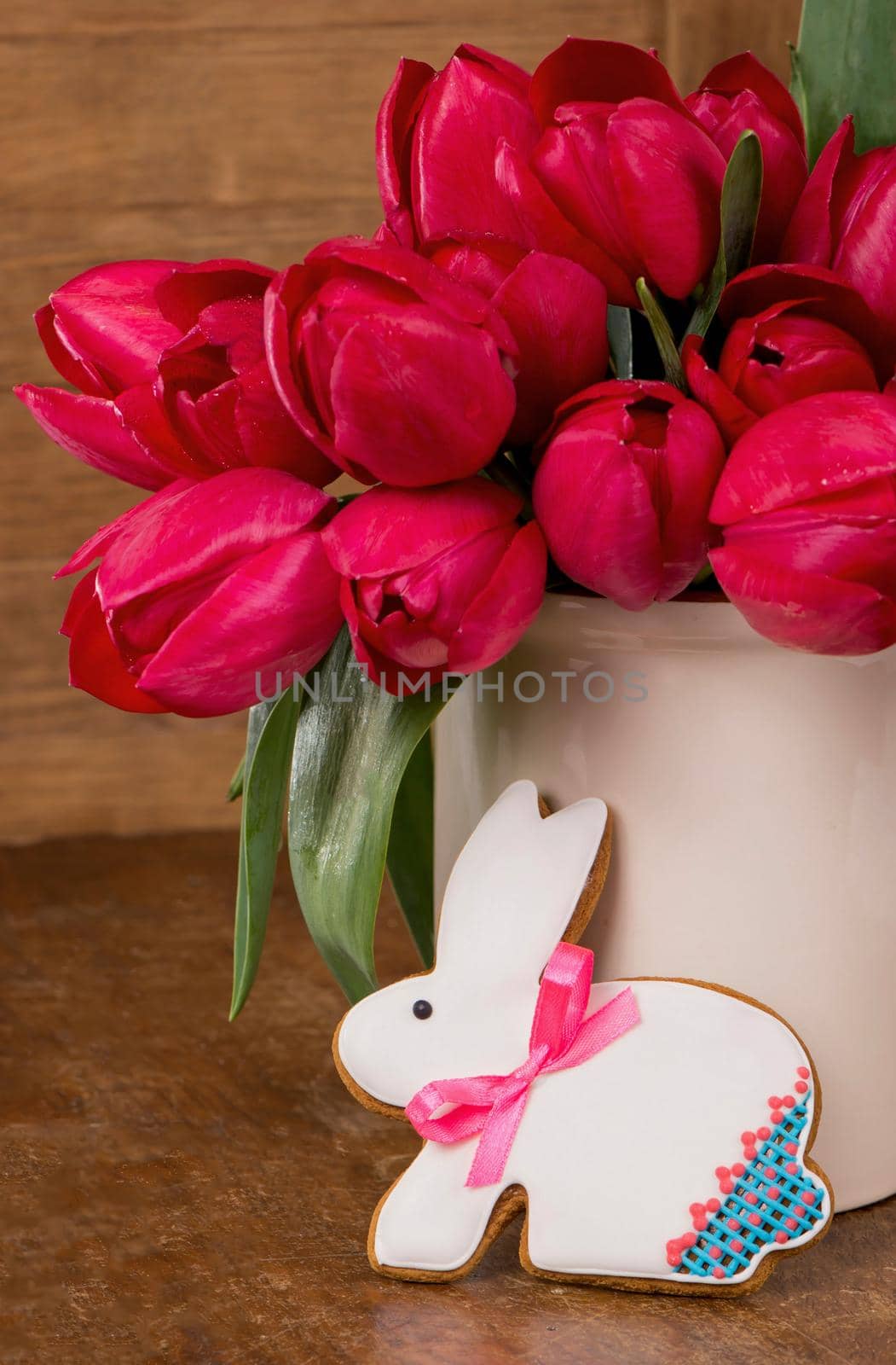 Pink tulips and easter bunny cookie on wooden background. by aprilphoto