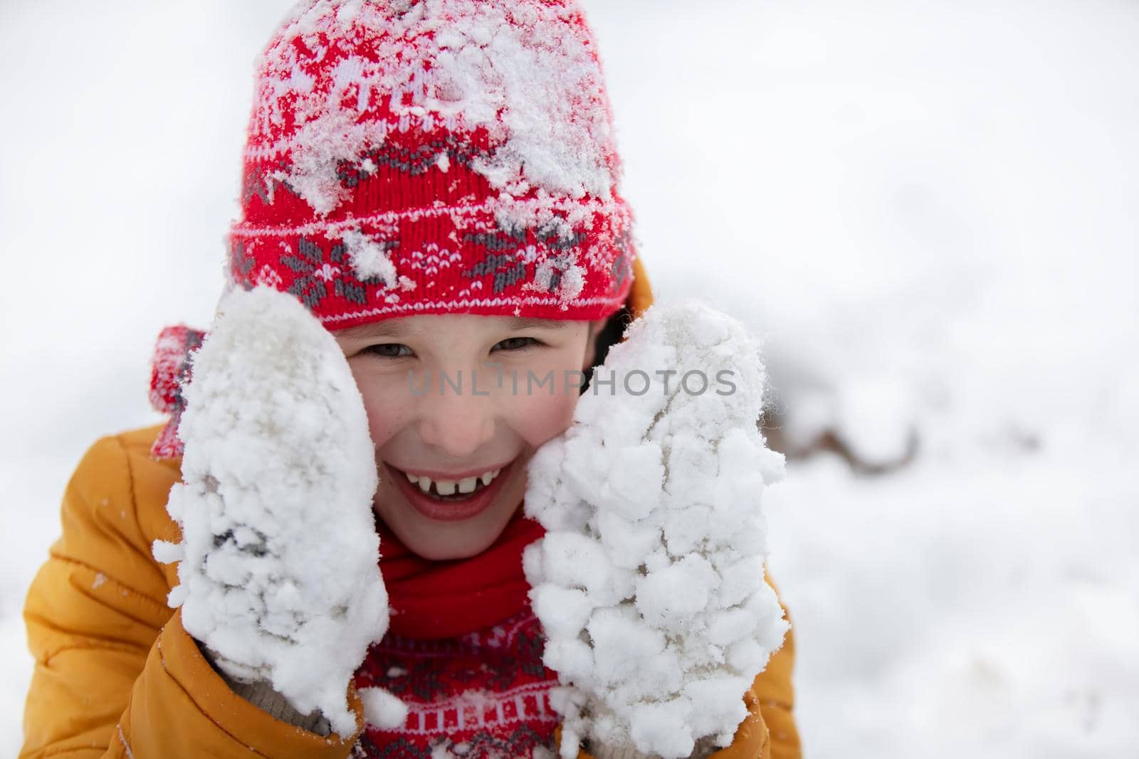 Happy little boy in winter in snow-covered mittens.