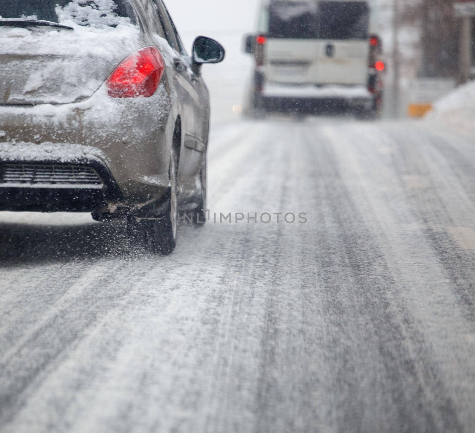 Road snow pieces flow from wheels of dirty car moving fast in daylight city with selective focus. by z1b