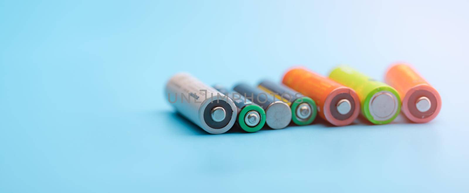 Rechargeable battery on blue background. Selective focus negative terminals of rechargeable lithium-ion batteries. AA and AAA size of old Li-ion battery. Battery recycling concept. Green power energy.