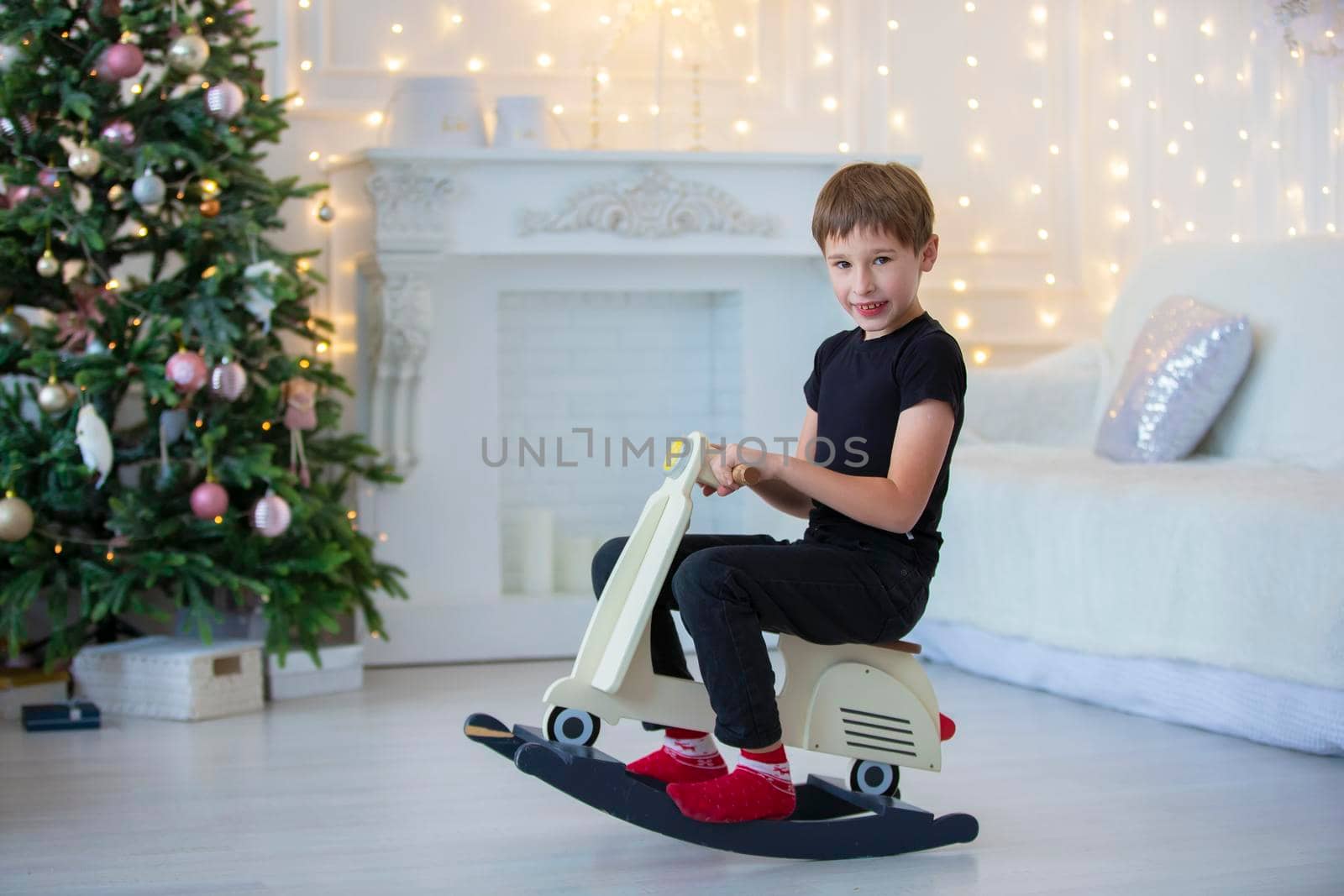 Handsome little boy in casual clothes is playing in the Christmas room.