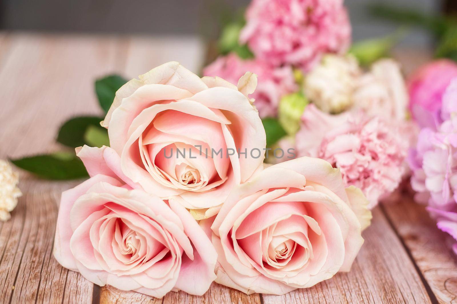 Close-up of different pastel roses in a bouquet on the table at the florist by galinasharapova