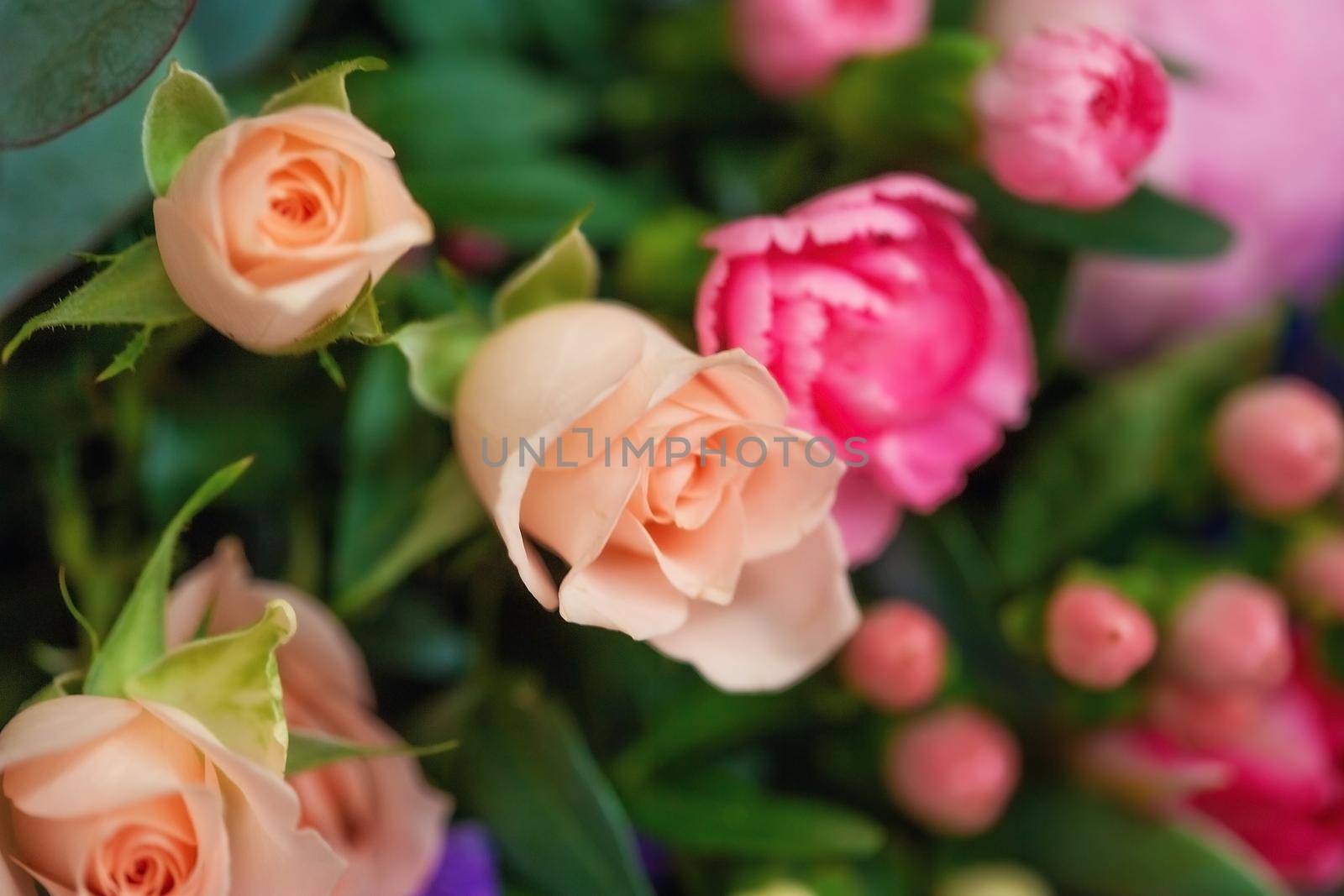 Close-up of different pastel roses in a bouquet on the table at the florist by galinasharapova