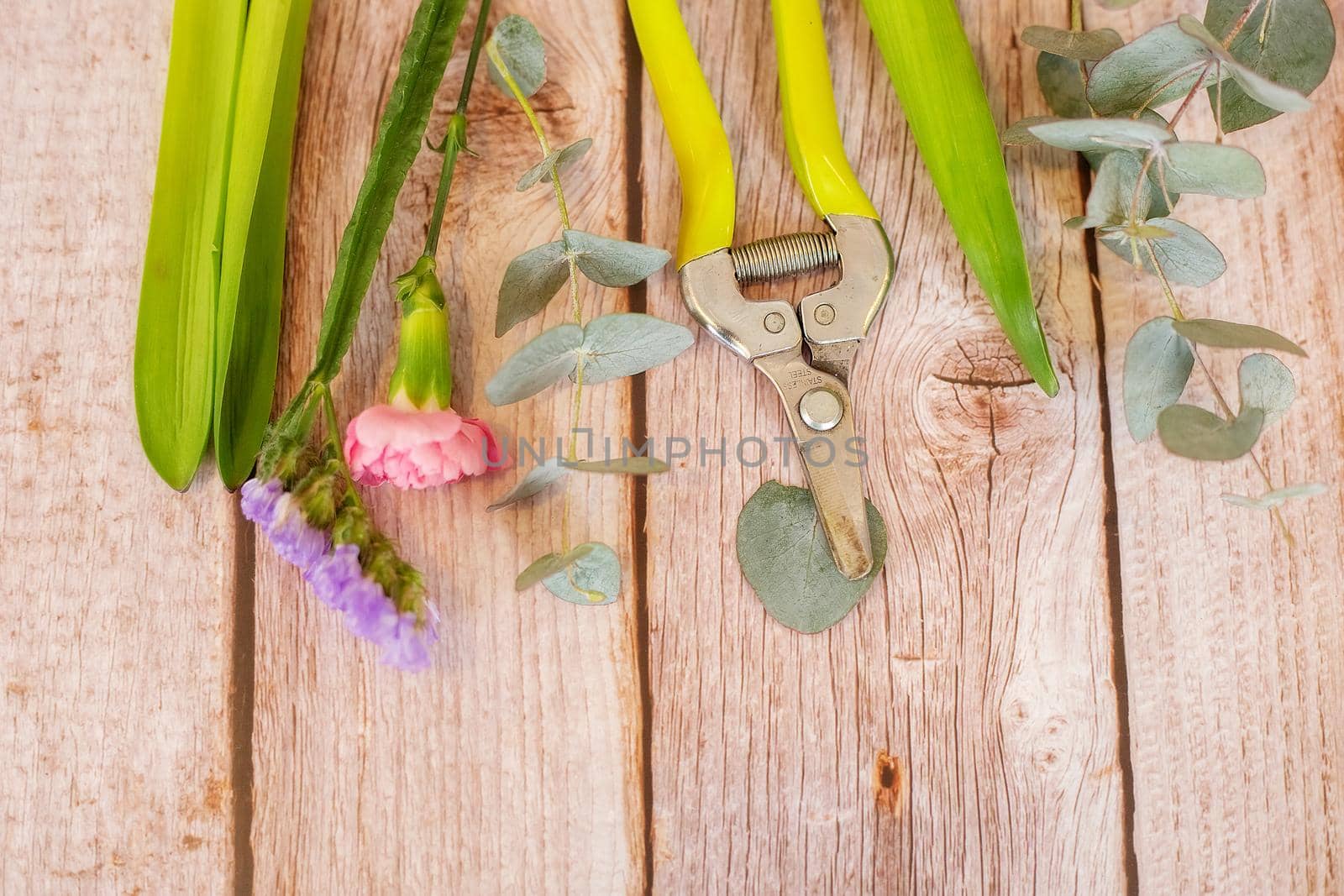 The florist desktop with working tools on light wooden background with place for text.