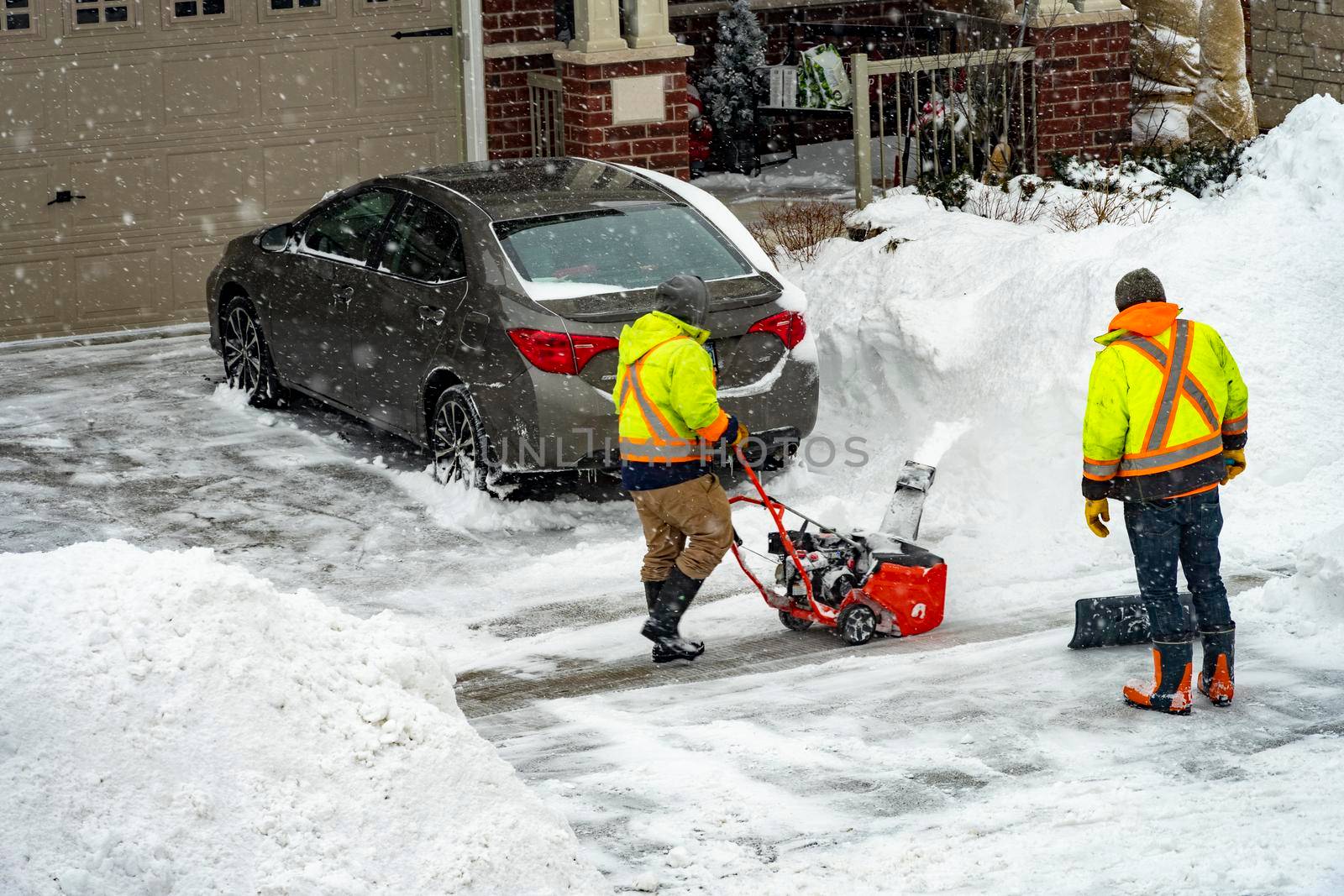 After a night storm, workers clear snow from the entrance to the garage