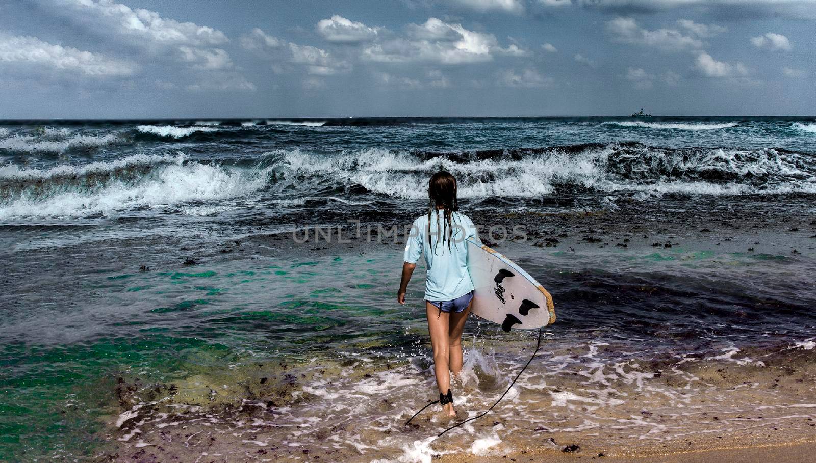 Young girl fearlessly goes into the sea to surf hoping to catch a big wave