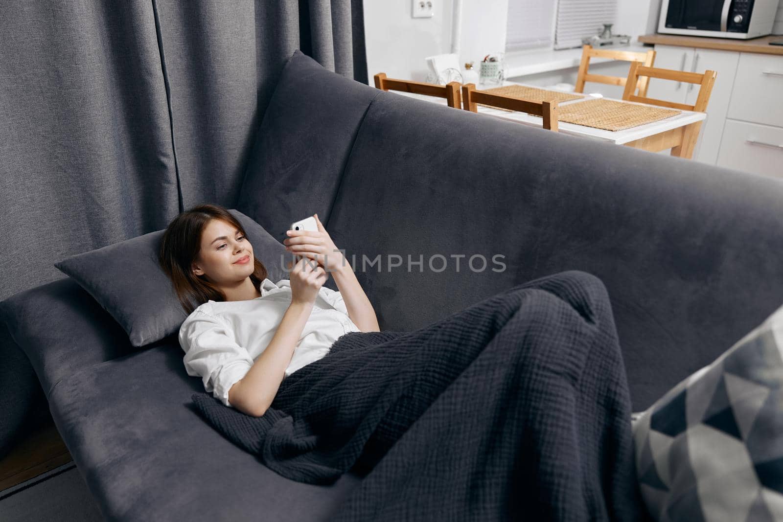 woman white t-shirt with a phone in her hand lies on the couch. High quality photo