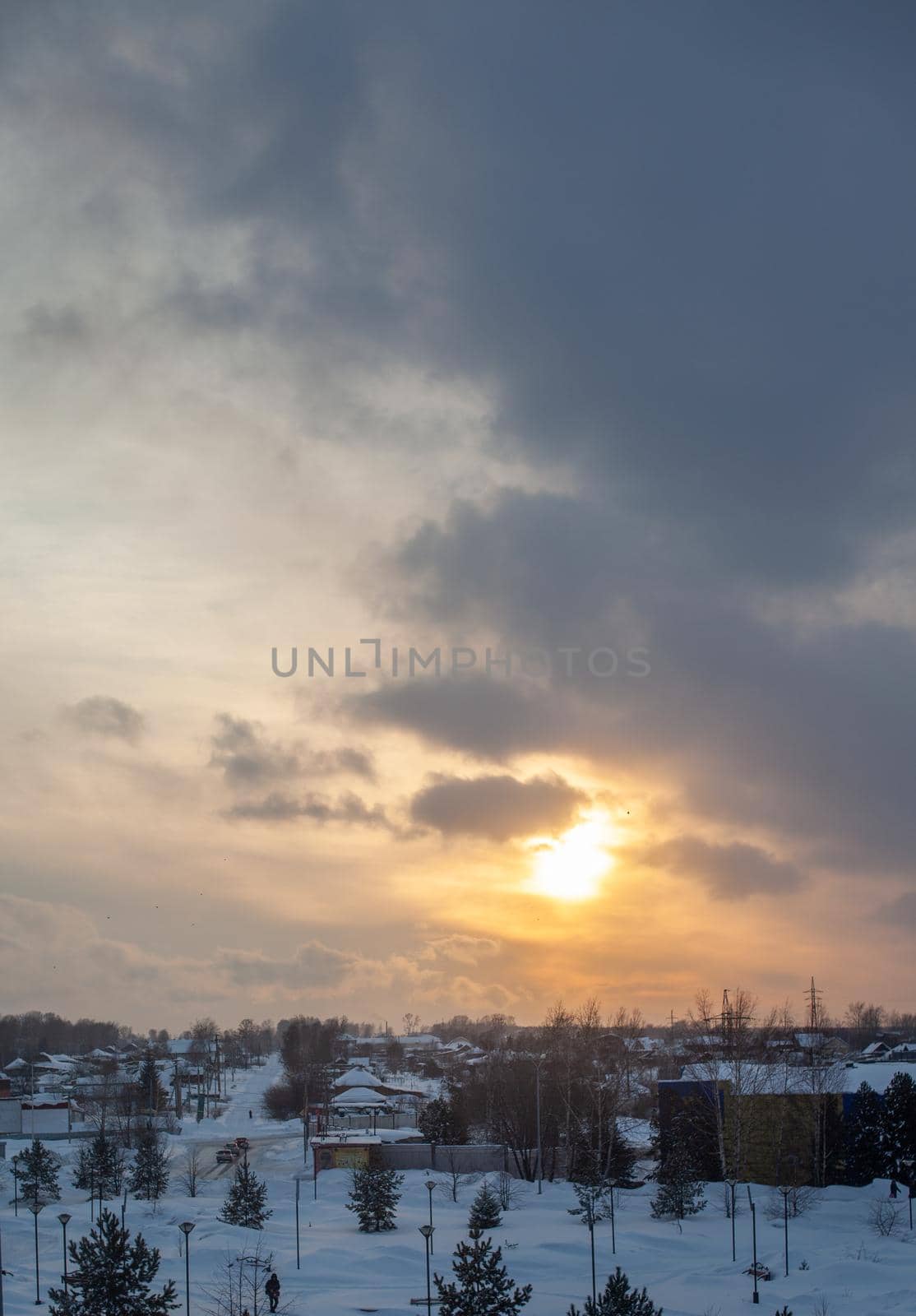 The sun among the clouds over the winter city. Beautiful background. The sky and clouds are painted in different colors.