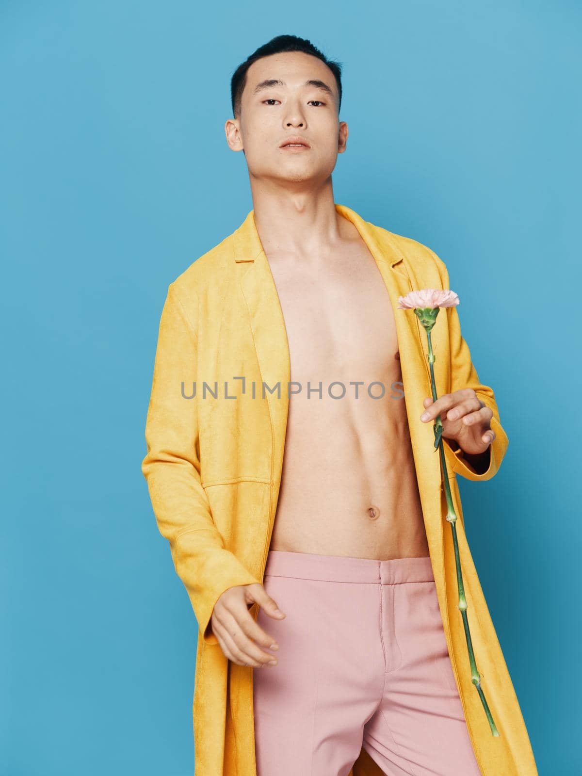 Korean man in a yellow coat with a flower in his hand and pink trousers. High quality photo