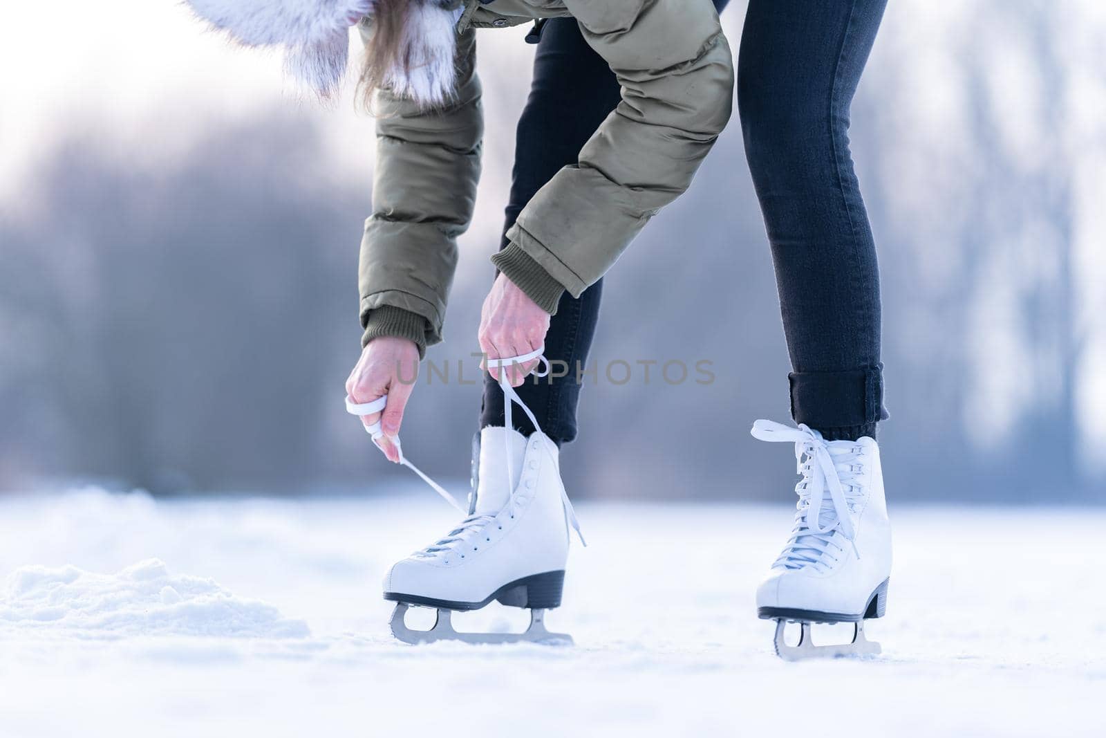 tying the laces of winter skates on a frozen lake