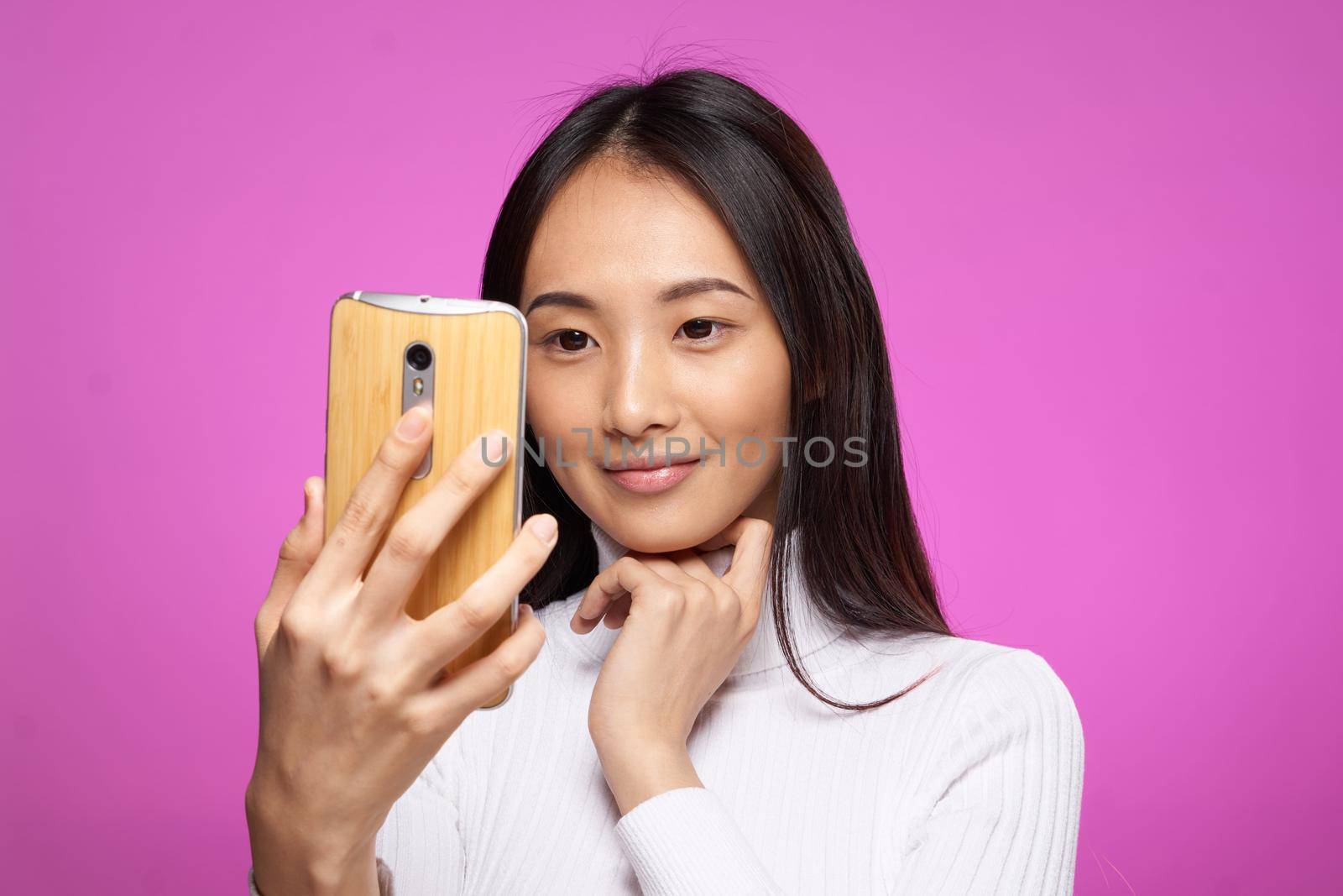 asian woman looking at phone internet technology pink background. High quality photo