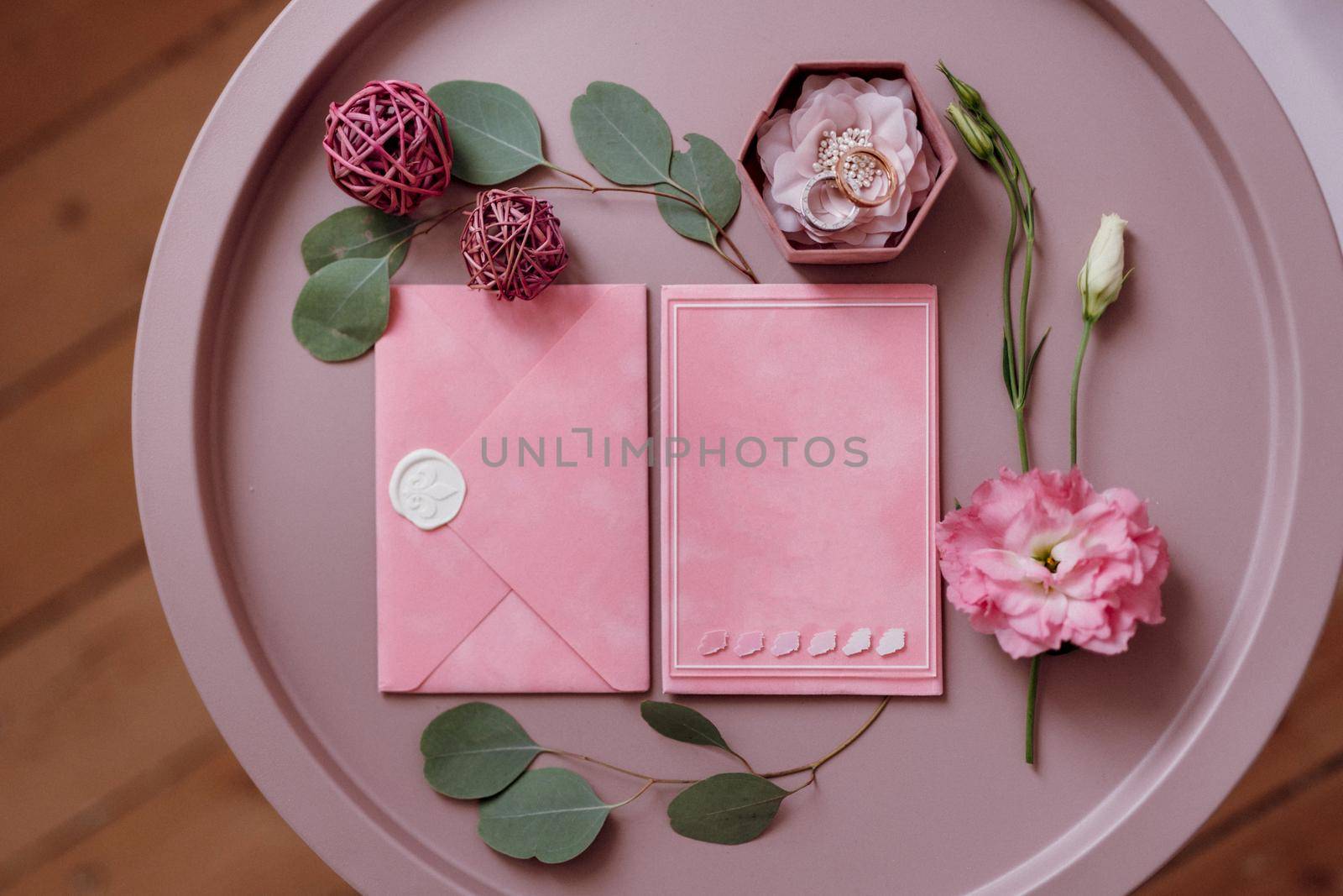 wedding invitation in a gray envelope on a table with green sprigs by Andreua