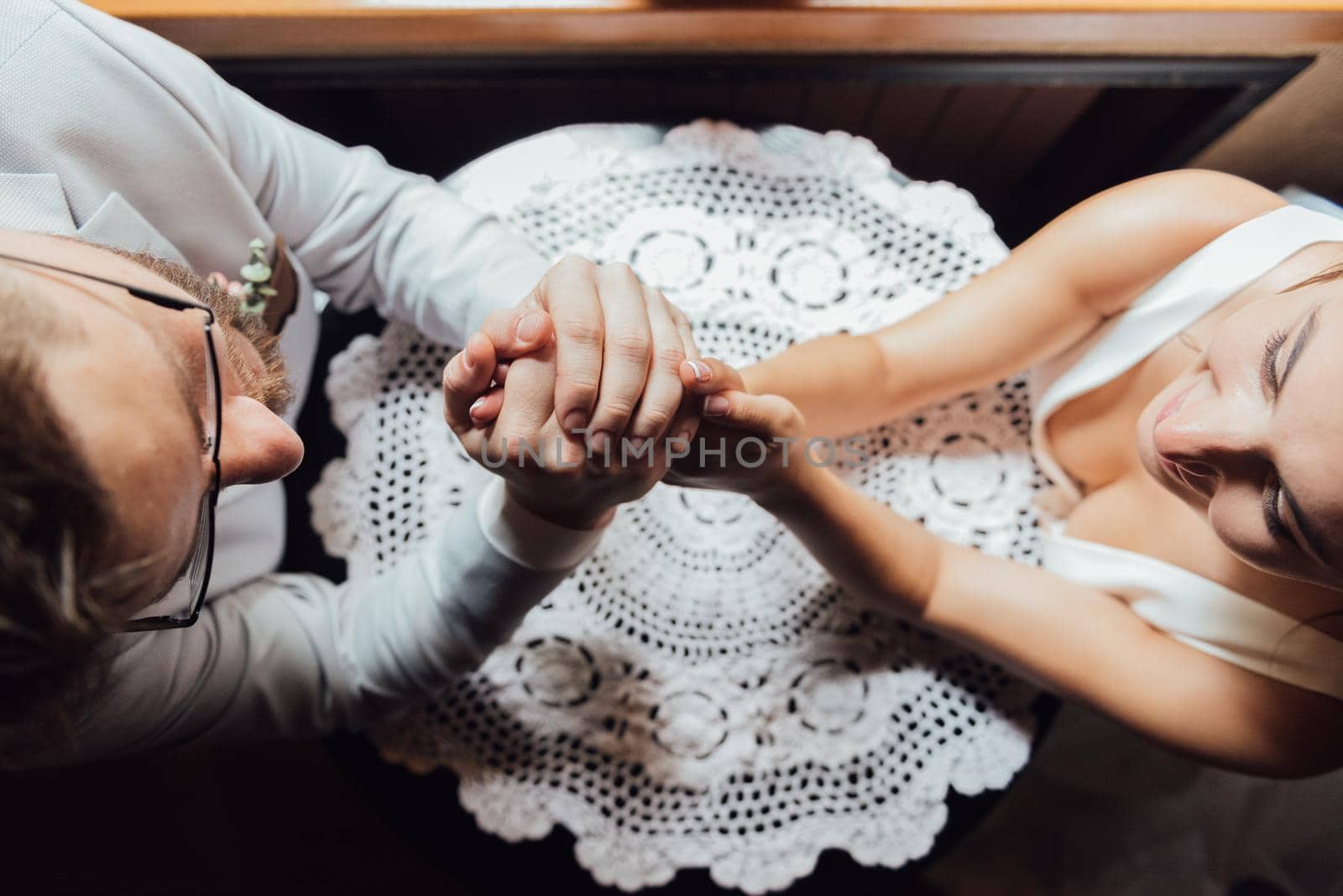 guy in a suit and a girl in a dress are sitting at the table and holding hands and looking into each other's eyes