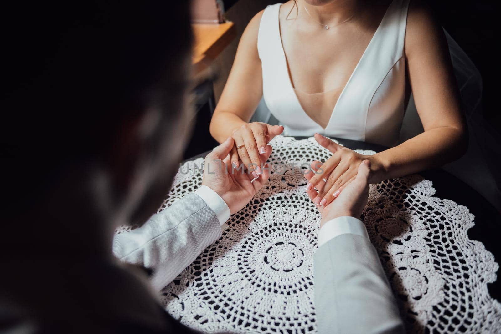 guy in a suit and a girl in a dress are sitting at the table and holding hands and looking into each other's eyes