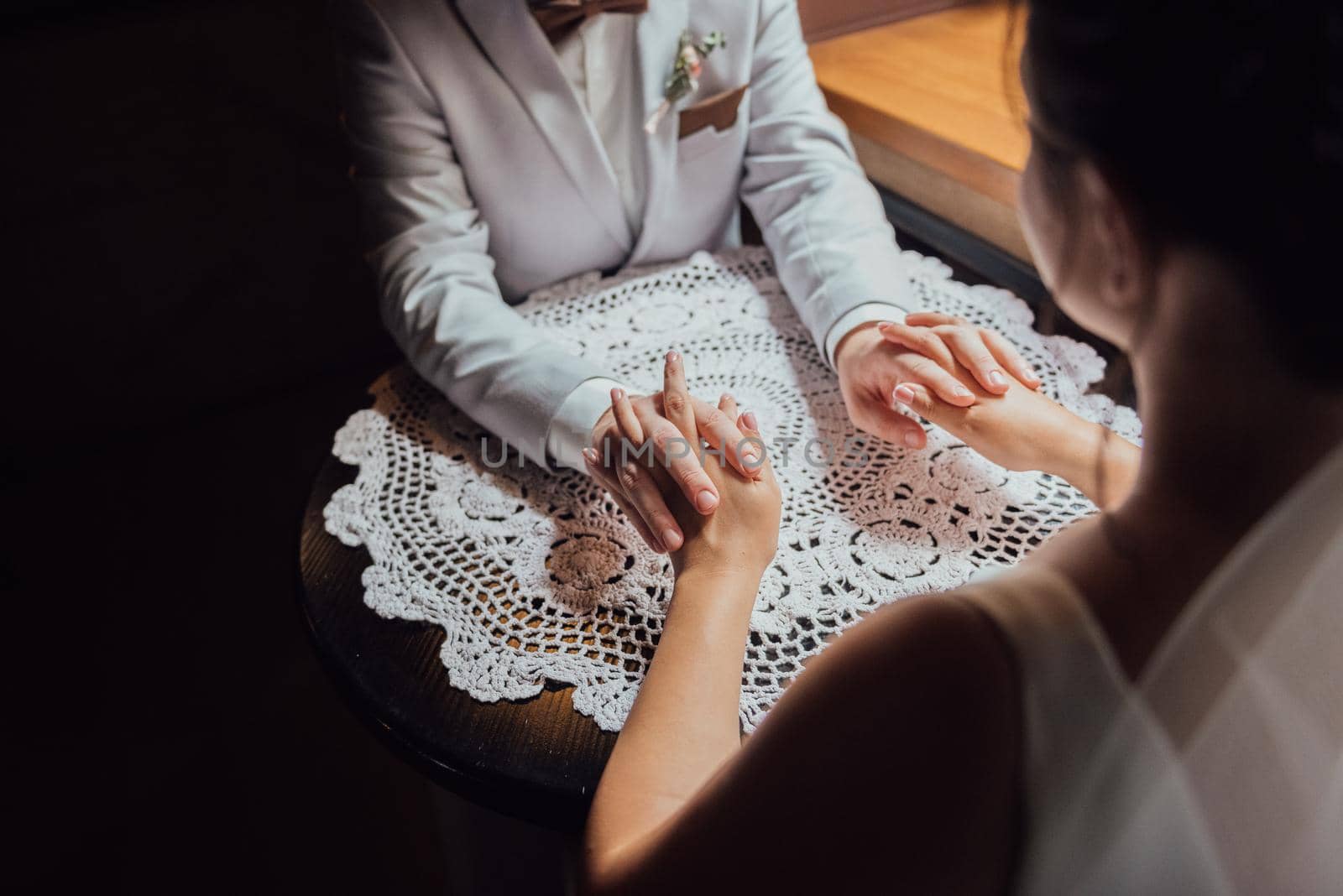 guy in a suit and a girl in a dress are sitting at the table and holding hands and looking into each other's eyes